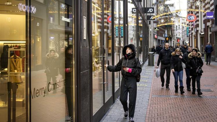 Eine Frau versucht nach Beginn des Lockdowns vergeblich einen geschlossenen Laden im Stadtzentrum zu betreten. In den Niederlanden hat kurz vor Weihnachten wegen der Omikron-Variante des Coronavirus ein harter Lockdown begonnen.