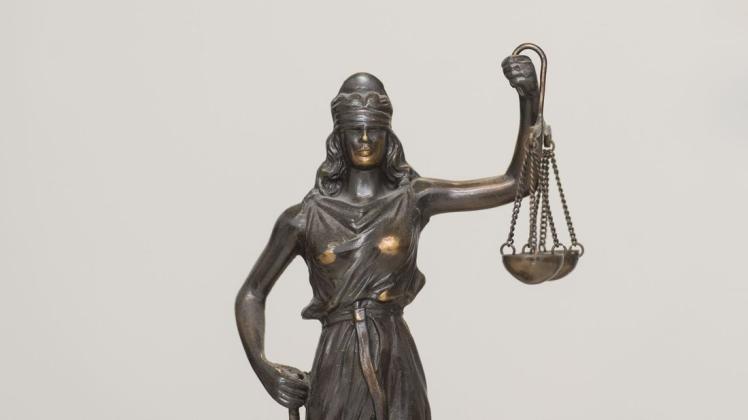 Eine Figur „Justitia“ steht auf einem Schreibtisch.