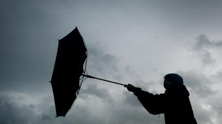 Der Regenschirm eines Spaziergängers wird von einer Windböe erfasst.
