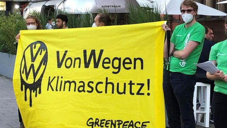 Demonstranten von Greenpeace demonstrieren mit einem Poster "VW - Von Wegen Klimaschutz!".
