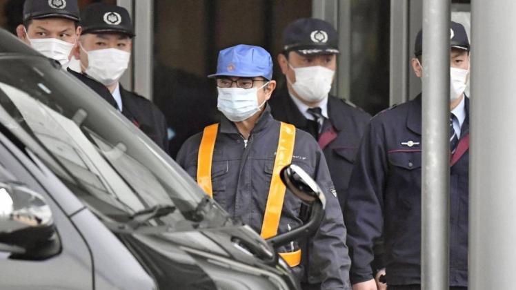 Carlos Ghosn (mit blauer Kappe) wird aus dem Gebäude eskortiert, in dem er drei Monate in U-Haft saß. Foto: imago images / Kyodo News