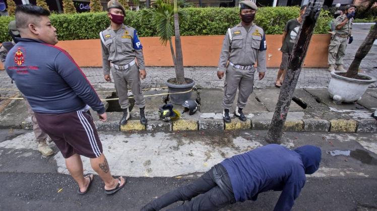 Ein Mann muss in Indonesien als Strafe gegen den Verstoß einer Maskenpflicht an öffentlichen Orten Liegestütze machen.