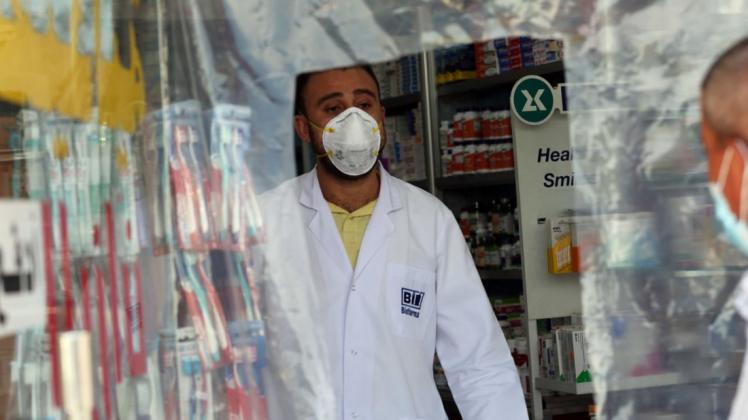 Irak, Bagdad: Ein Mitarbeiter einer Apotheke steht aufgrund des neuartigen Coronavirus hinter einer Kunststoffplane. Foto: XinHua/dpa