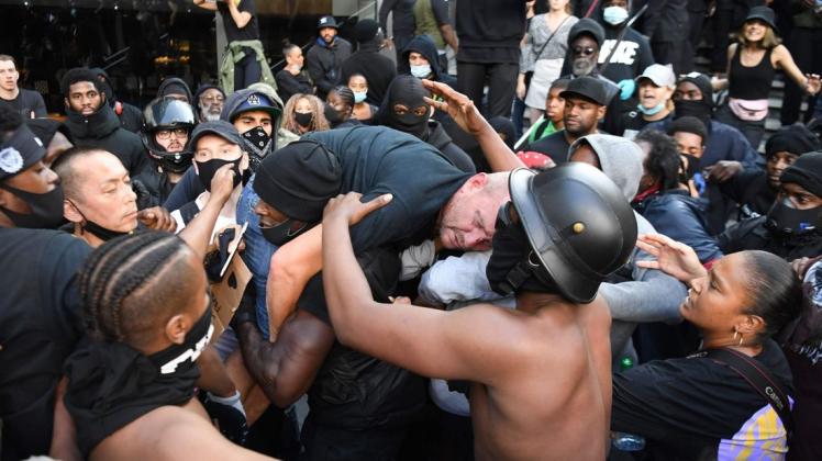 Ein Demonstrant der "Black-Lives-Matter"-Bewegung trägt einen verletzten Gegendemonstranten aus der Kampfzone.