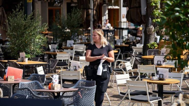 Eine Kellnerin desinfiziert Tische in Den Haag.