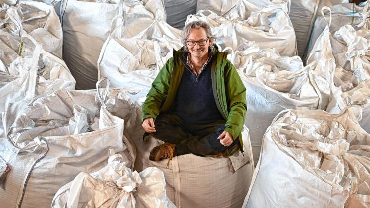 Landwirt Wilhelm Schäkel sitzt auf der Bio Ranch in einer Scheune auf Säcken voller Tee, Körner und Biomasse aus verschiedenen Hanfsorten.