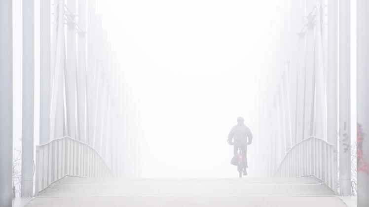 Ein Mann fährt mit einem Fahrrad bei Nebel über eine Straße. Besonders im Winter müssen Radfahrer extrem aufpassen im Straßenverkehr.