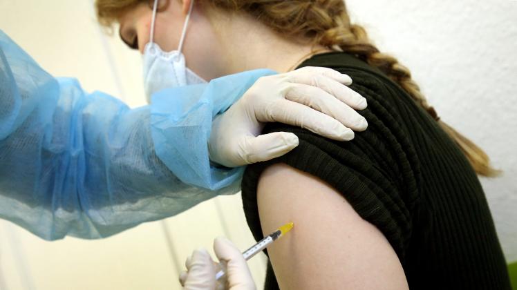 Eine junge Frau bekommt in der Praxis ihrer Hausärztin ihre Booster-Impfung.