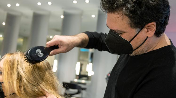Shan Rahimkhan, Berliner Friseur, bürstet einer Kundin in seinem Friseursalon die Haare.