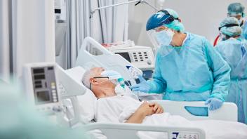 Doctor Talking to Senior Patient In Hospital During COVID-19