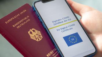 Für Reisen in der EU ist der Impfstatus wichtig. Symbolfoto mit dem digitalen COVID-Zertifikat und einem deutschen Reisepass. 