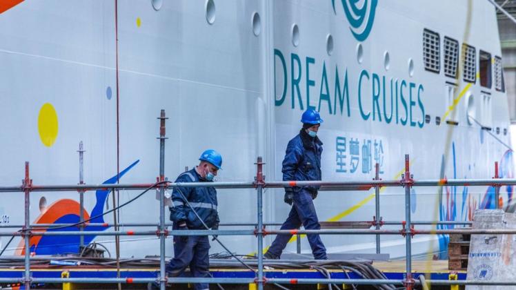 Schiffbauer arbeiten im Baudock der Schiffbauhalle vor dem im Bau befindlichen Kreuzfahrtschiff „Global Dream“ für die Reederei Dream Cruises.