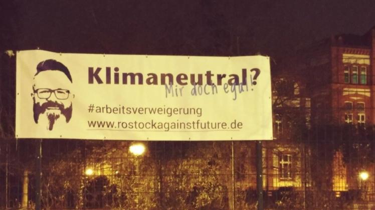 Mit einem Banner kritisieren Aktivisten den Einsatz des Rostocker OBs Claus Ruhe Madsen (parteilos) zur Erreichung des Ziels, bis 2035 klimaneutral zu werden.