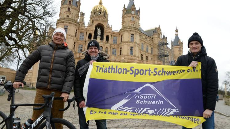 Vereinsfahne als symbolischer Staffelstab übergab Volkmar Müller (M.) an die Organisatoren des "Schwerin-Triathlon", Michael (l.) und Dennis Kruse.