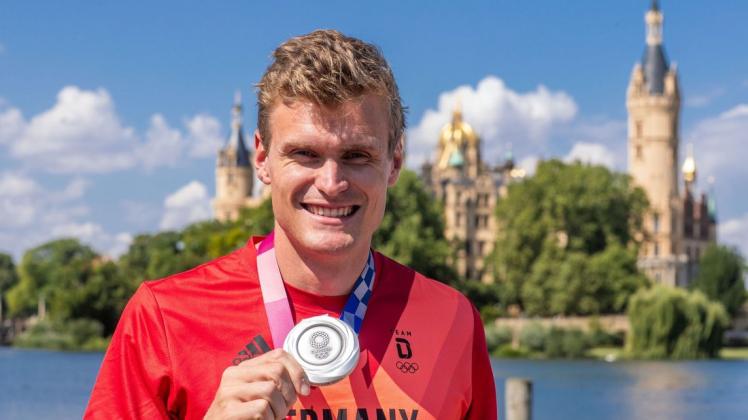 Hannes Ocik, Schlagmann im deutschen Ruderachter bei den Olympischen Spielen in Tokio, steht mit seiner Silbermedaille beim Empfang vor dem Schweriner Schloss.