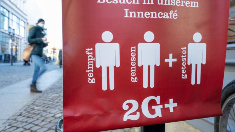 Ein Schild weist auf die 2G Plus Regel in einem Café im Ostseebad auf Rügen hin.   
