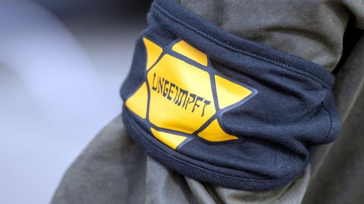 Bei einer Demonstration gegen die Einschränkungen durch die Pandemie-Maßnahmen der Bundesregierung  trägt ein Teilnehmer eine Armbinde mit einem gelben Stern, der an einen Judenstern erinnern soll.