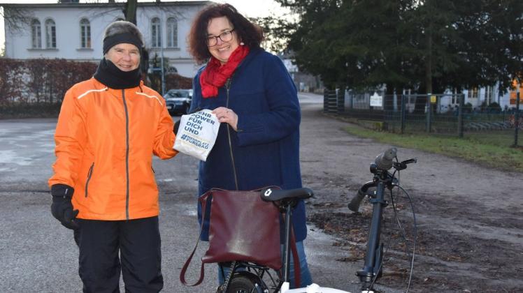 Schwingt sich trotz eisiger Kälte am frühen Morgen aufs Fahrrad: Sandra Pohl (r.). Als Dankeschön erhält sie von Madleen Kröner vom ADFC in Schwerin einen Frühstücksbeutel.