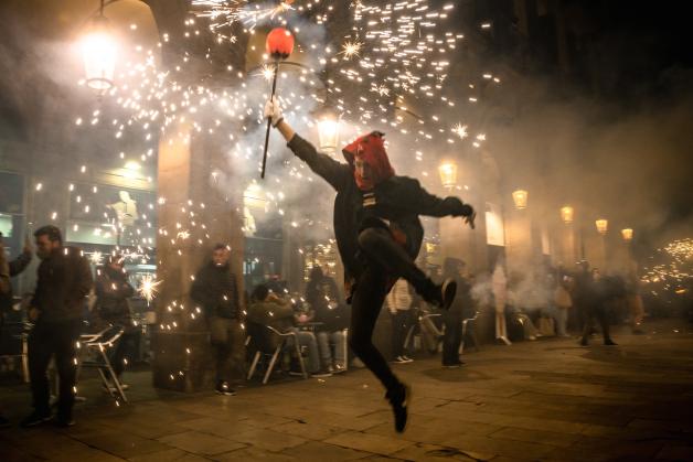 Ein Feuerläufer springt mit seinem Teufelskostüm durch die Straßen der Stadt Barcelona.