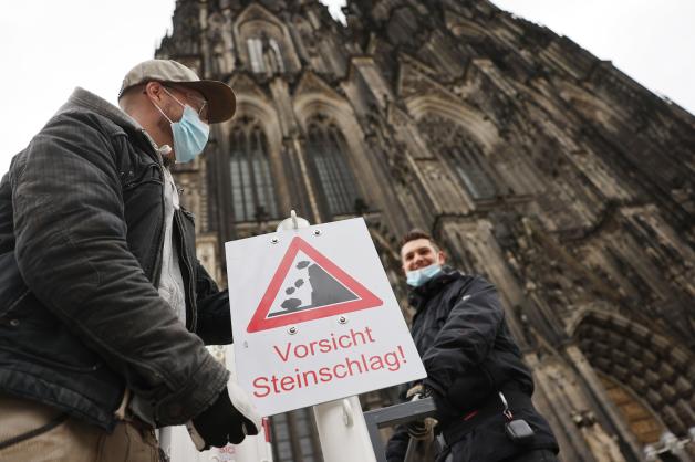 Achtung, der Wind könnte Steine fliegen lassen! Am Kölner Dom wird ein Schild aufgestellt. Bei diesem Wetter sollte man draußen sehr vorsichtig sein. 