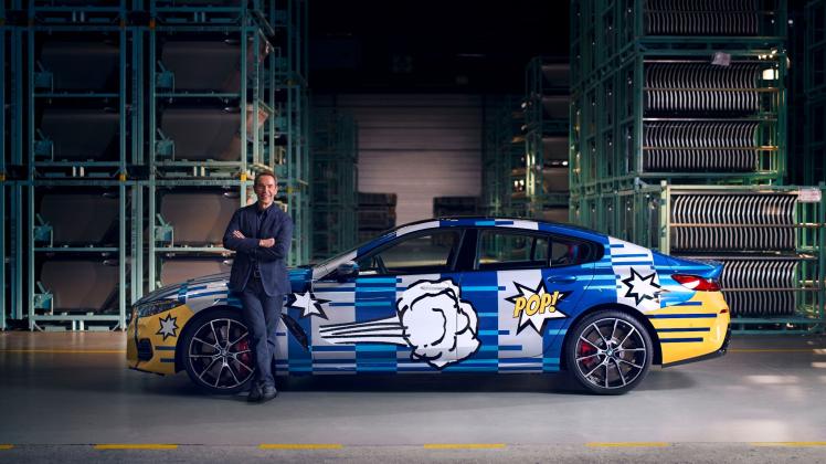 Jeff Koons steht seitlich vor einem von ihm gestalteten BMW.