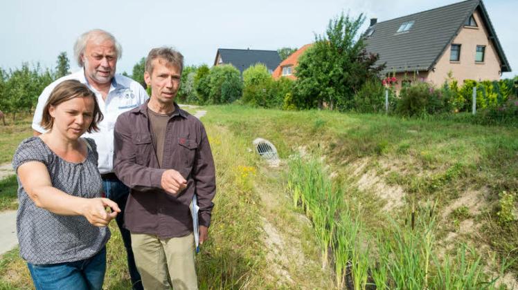 Bei der Begehung erklären Ingenieurin Juliane Müller und Norbert Wieting vom Umweltamt (r.) Anwohner Felix Walter das neu entstandene Grabensystem, das Evershagen-Dorf in Zukunft besser vor Hochwasser schützen soll.  