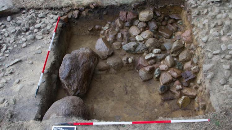 Ausgrabungsfund: Zwei Steine des Steinrings um den Grabhügel, rechts davon Reste des „Ringankers“ und der bronzezeitlichen Pflasteroberfläche.