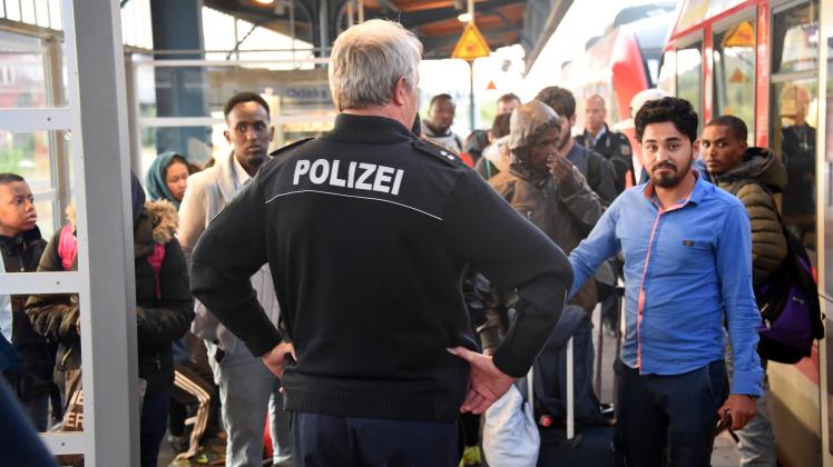 Ein Beamter der Bundespolizei hält auf dem Bahnhof in Flensburg Reisende auf, um sie zu kontrollieren. /Archiv