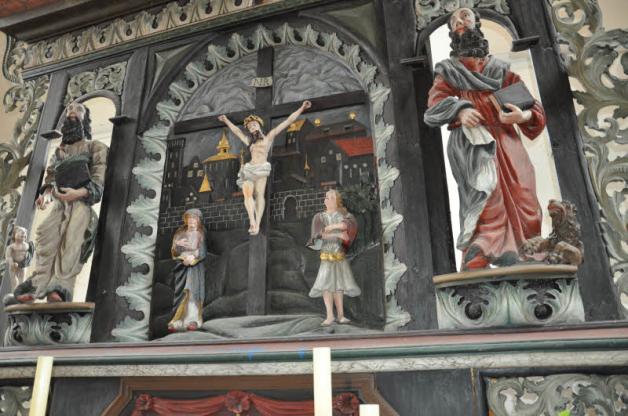 Die Figur rechts neben dem Kreuz irritiert einen aufmerksamen Besucher durch recht knappe Bekleidung .
