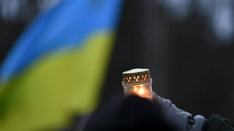 A protester holds a candle in front of the Ukrainian flag as people demonstrate against Russia s invasion of Ukraine in