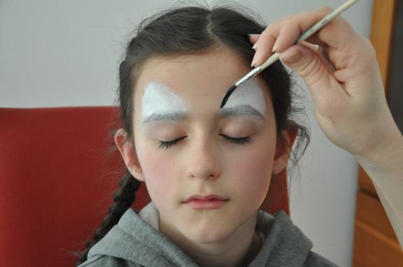 3. Lass dich nun von jemandem schminken: Über den Augen weiße Dreiecke, die mit Schwarz umrandet werden. Neben den Augen vielleicht noch ein paar Striche und auf der Stirn zwei V-Zeichen. Zusätzlich kann auch die Nase und die Mundpartie geschminkt werden. Wenn du sowieso vor hast, deine FFP2-Maske zu tragen, kannst du das auch weglassen. 3. Lass dich nun von jemandem schminken: Über den Augen weiße Dreiecke, die mit Schwarz umrandet werden. Neben den Augen vielleicht noch ein paar Striche und auf der Stirn zwei V-Zeichen. Zusätzlich kann auch die Nase und die Mundpartie geschminkt werden. Wenn du sowieso vor hast, deine FFP2-Maske zu tragen, kannst du das auch weglassen.