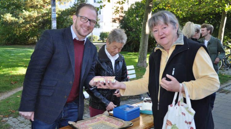 Auf dem Boulevard verkaufen Steffen Bockhahn (Linke) und Gabriele Bolz (CDU, M.) Kuchen an Jenny Giebel.