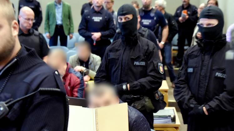 Polizeibeamte eines Spezialeinsatzkommandos stehen im Verhandlungssaal des Landgerichtes Schleswig hinter und neben den Angeklagten.