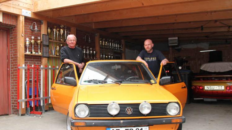 Erfolgreiche Motorsportler: Den orange-farbenen Polo als Wettkampf-Fahrzeug teilen sich Egon (links) und Thomas Büssert. Auch die Regale für die Pokale im Hintergrund nutzen Vater und Sohn gemeinsam.