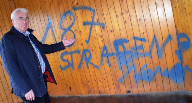 Bürgermeister Kurt Lindemann ärgert sich über das Graffiti, mit dem die Holzwand im Buswartehäuschen besprüht wurde.