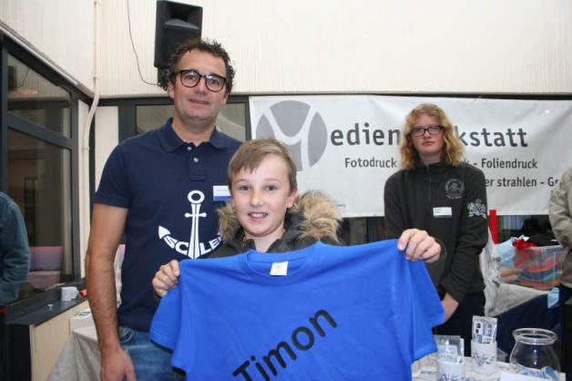 Timon Raatz  kaufte bei Swantje Dippel aus der Medienwerkstatt ein T-Shirt, links Betriebsstättenleiter Marc Müller.