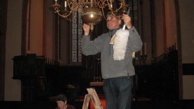 Gemeindekirchenratsmitglied Egbert Babekuhl verleiht dem Leuchter frischem Glanz.