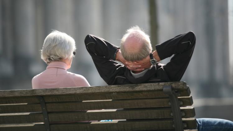 Ein Rentnerpaar sitzt auf einer Bank und sonnt sich.  