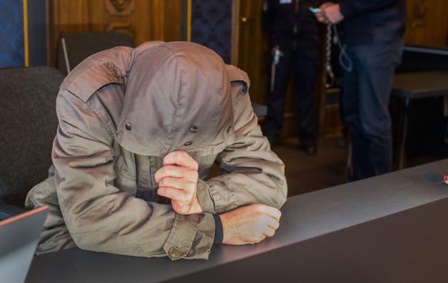 Der Angeklagte Peter B. versteckt im Verhandlungssaal des Landgerichts Schwerin sein Gesicht