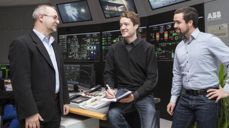 Kraftwerksleiter Axel Becker (v. l.) bespricht mit den Forschern der Uni Rostock Moritz Hübel und Conrad Gaserow die aktuelle Betriebssituation auf der Leitwarte des Rostocker Kraftwerks.   