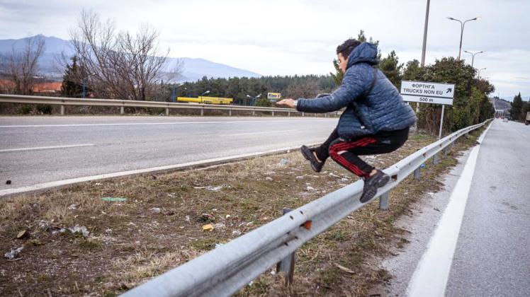 Ein junger Mann aus Algerien springt über die Leitplanke einer Straße, die zur griechisch-mazedonischen Grenze führt. Dort ist seit Anfang März der Grenzübertritt illegal. 