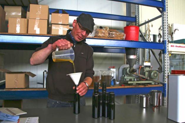 Hier ist alles noch Handarbeit: Ingo Sander füllt frisch gepresstes Leinöl in Flaschen aus ultraviolettem Glas. Das lässt nur eine geringe Menge Licht an das Öl und verbessert sogar die Haltbarkeit.