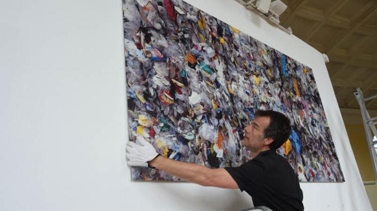 Florian Wilk hängt die Collage „Waste“ auf.  Fotos: Klawitter (3) 