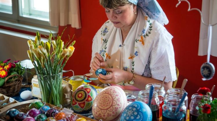 In einer traditionellen sorbisch-wendischen Tracht sitzt Martina Riedel im Spreewald-Museum in Lübbenau und verziert Eier.