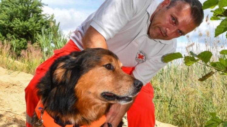 Hundeführer Christian Arlt vom DRK legt seinem Wasserortungshund Oscar eine Schwimmweste an. 