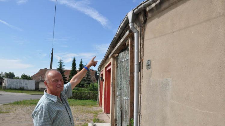 Die Bauschäden am Gerätehaus in Prestin  sind nicht zu übersehen: Bürgermeister Klaus Aurich zeigt auf die beschädigte Wand und die abgestützte Einfahrt zum gesperrten Teil.  