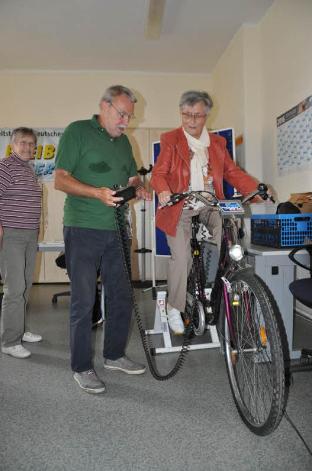 Gerd Vollstett mit einer Besucherin am Fahrradsimulator