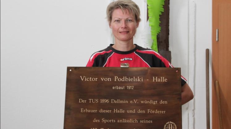 TuS-Vereinsvorsitzende Diana Küchler präsentiert die Namenstafel für die Turnhalle.