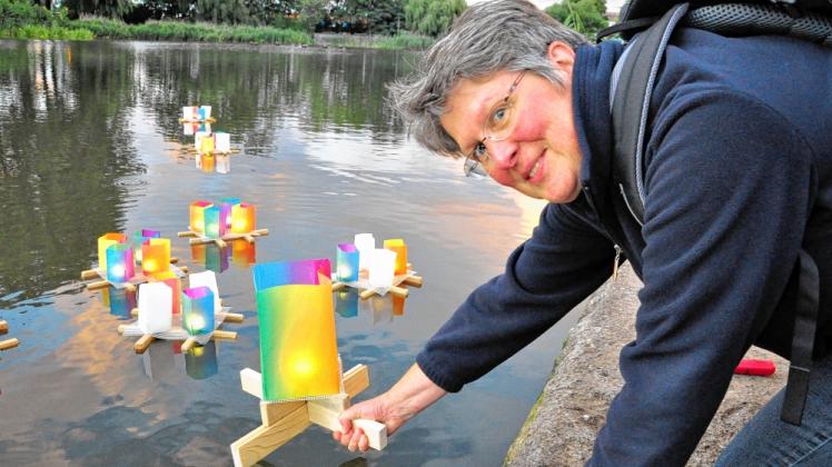 Farbenspiel auf dem Schwanenteich: Behutsam lässt Christa Petersmann die bunten Kerzen auf das Wasser gleiten. Sie ist seit Kurzem Mitglied des Rostocker Friedensbündnisses. 