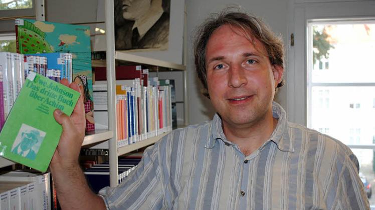 Tilmann Wesolowski zieht in der Uwe-Johnson-Bibliothek „Das dritte Buch über Achim“ aus dem Regal, aus dem am 22. September gelesen wird.  
